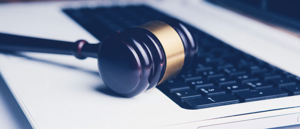 A judge's gavel resting on a laptop keyboard, symbolizing the intersection of law and technology.