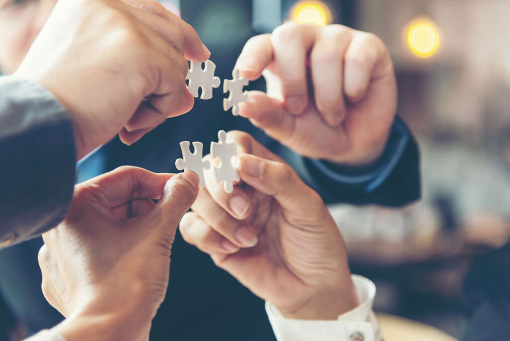 Business professionals collaboratively assembling puzzle pieces, symbolizing teamwork and problem-solving.