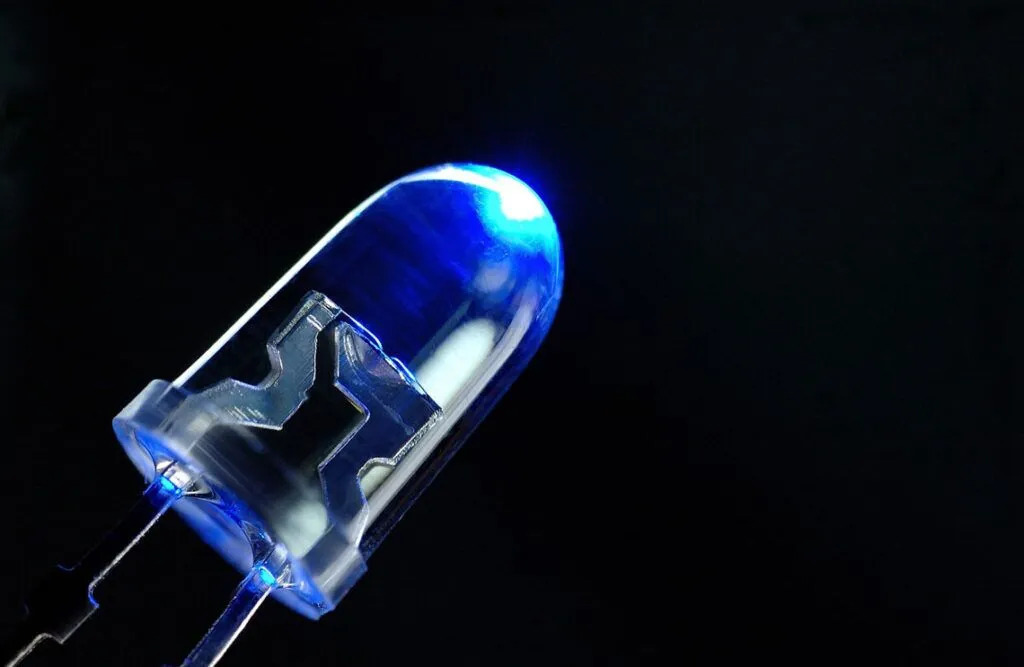A blue LED light bulb illuminated against a solid black background.